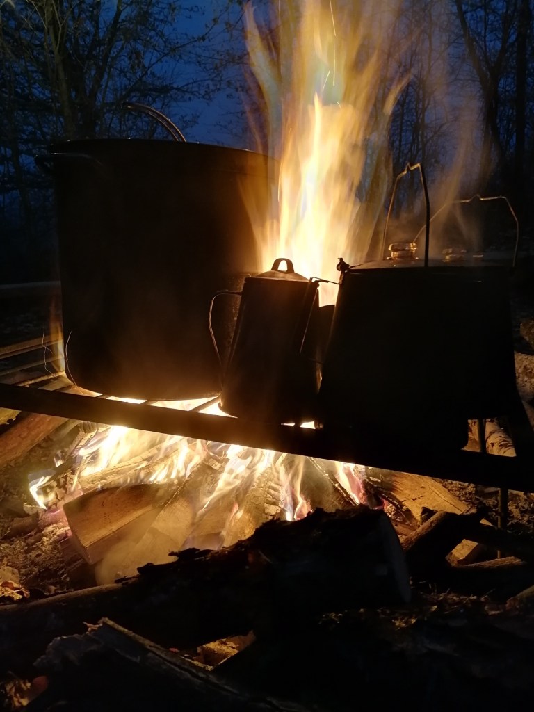 Kannen und ein Topf auf einer Feuerstelle in einem Wildkräuterseminar.